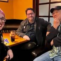 Three alums sitting together at a table.